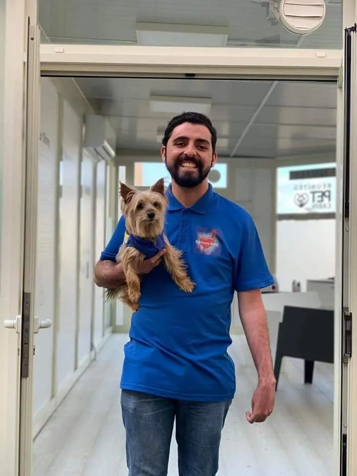 Jacob in a Survivors Malta polo shirt, holding Peanut in the doorway of the Reunited Pet Cabin