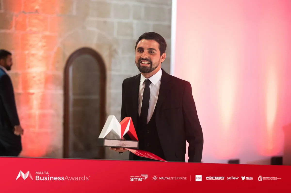 Jacob on stage at the Malta Business Awards, holding the red and white trophy for Best CSR Initiative